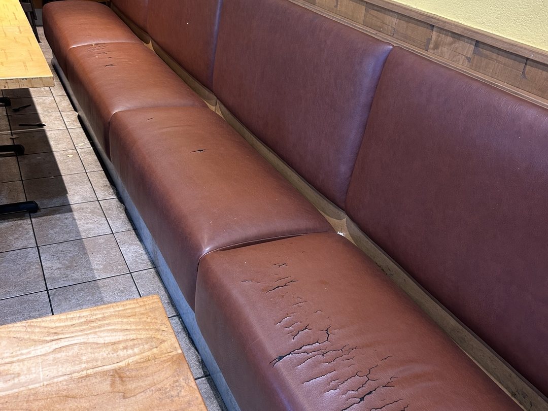 Cracked burgundy vinyl wall banquette at a San Diego Rubio's Coastal Grill before commercial reupholstery