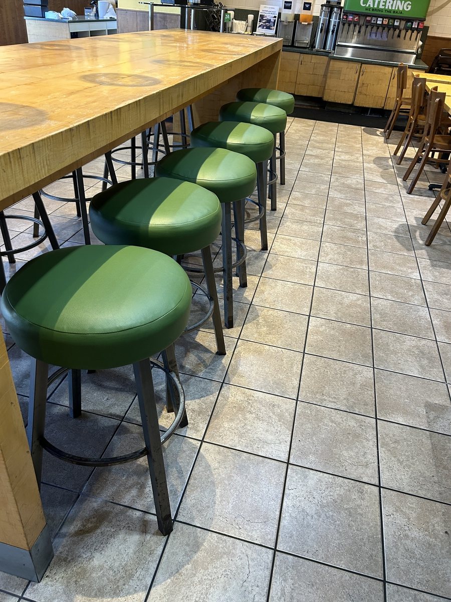 Reupholstered green vinyl bar stools lined up at a San Diego restaurant counter after a full seating restoration